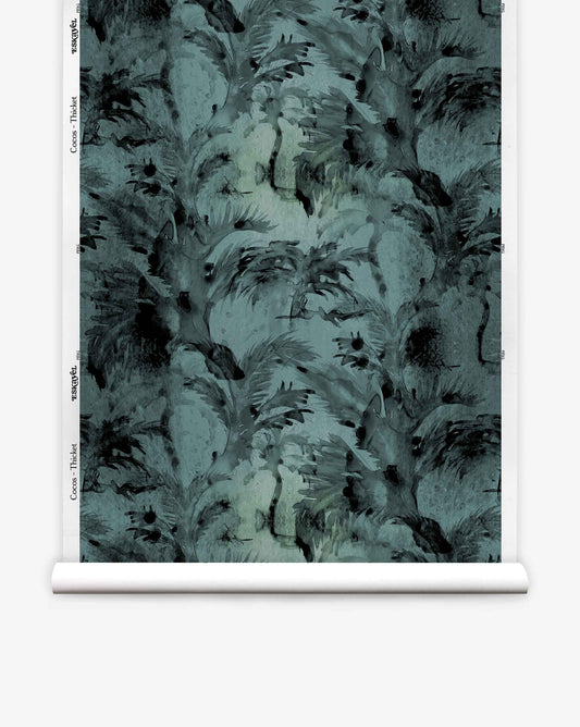 A roll of Cocos Silk Wallcovering||Thicket is displayed vertically against a white background, featuring a luxurious dark teal abstract feather pattern that evokes the refined texture of grasscloth wallpaper with subtle hints of palm tree motifs.