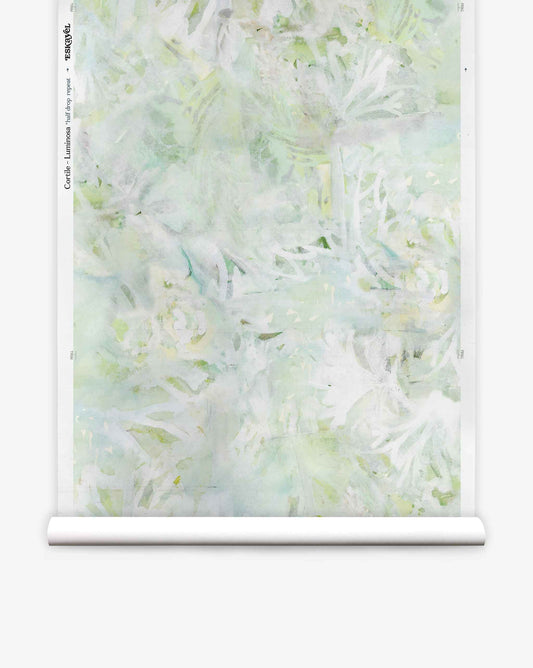 A roll of Cortile Silk Wallcovering||Luminosa, featuring a pale green and white abstract floral pattern inspired by an Italianate garden, is partially unrolled against a white background.