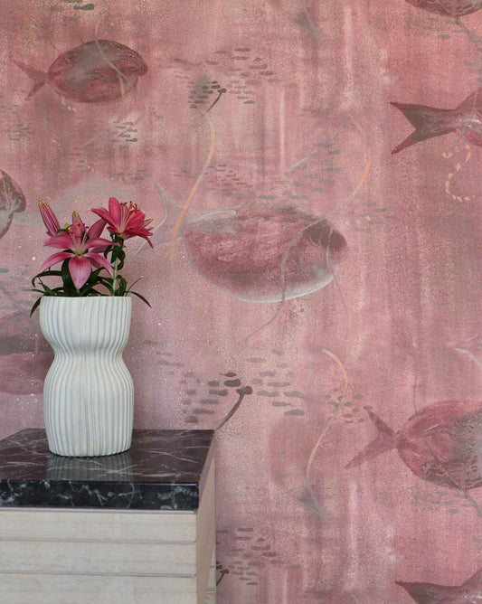 Eskayel’s Shoal wallpaper in Coral with its red hues is printed on paper backed silk and installed in a room behind a side table with a vase of flowers on top.