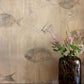 Eskayel’s Shoal wallpaper in Shell with its beige hues is printed on paper backed silk and installed in a room behind a wooden table with a vase of flowers on top.
