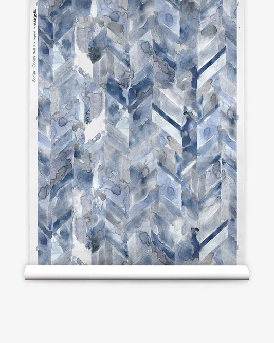 Sorisa Silk Wallcovering||Ocean features a watercolor-style paper-backed wallpaper with blue and gray ink-wash chevron geometric patterns displayed vertically.