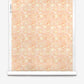A roll of Yaya Silk Wallcovering in Grapefruit, featuring an abstract, tonal pattern of layered coral and cream shapes.