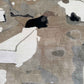 Abstract area rug with an organic, painterly pattern in beige, taupe, gray, off-white, and black.