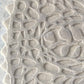 In the Blanca colorway, a Nonna’s Lace rug swatch shows the silk and wool pattern in creamy beige neutral tones.