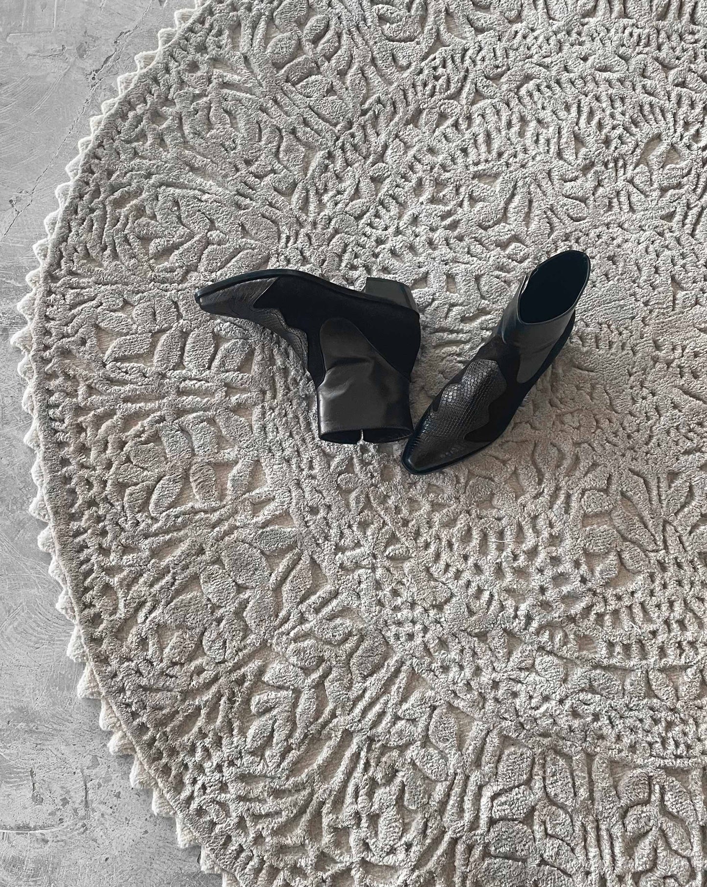 Black high-heeled shoes on our Nonna's Lace round rug in the colorway neutral.