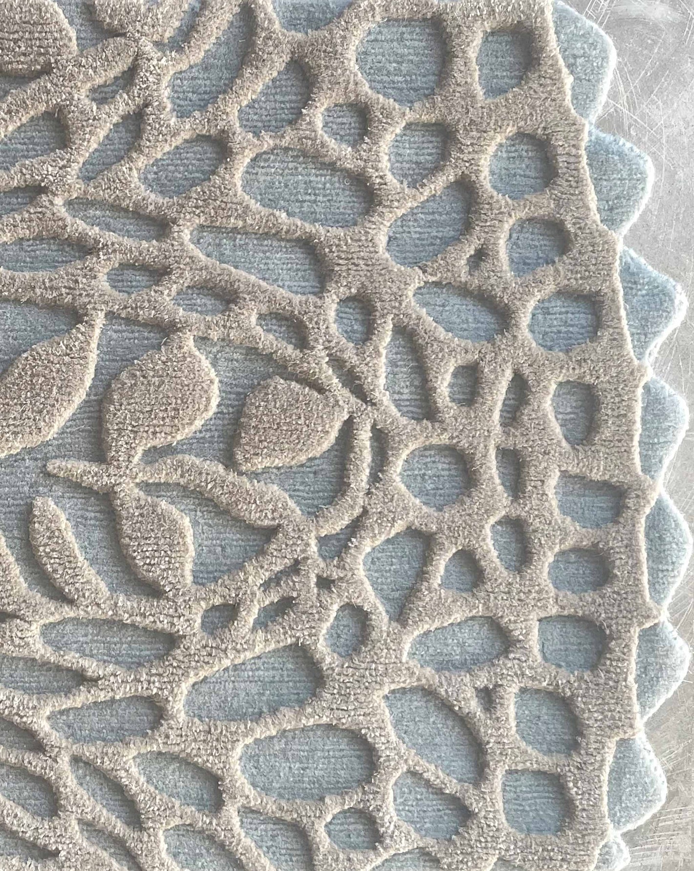 In the Cielo colorway, a Nonna’s Lace rug swatch shows the silk and wool pattern in blue and neutral tones.