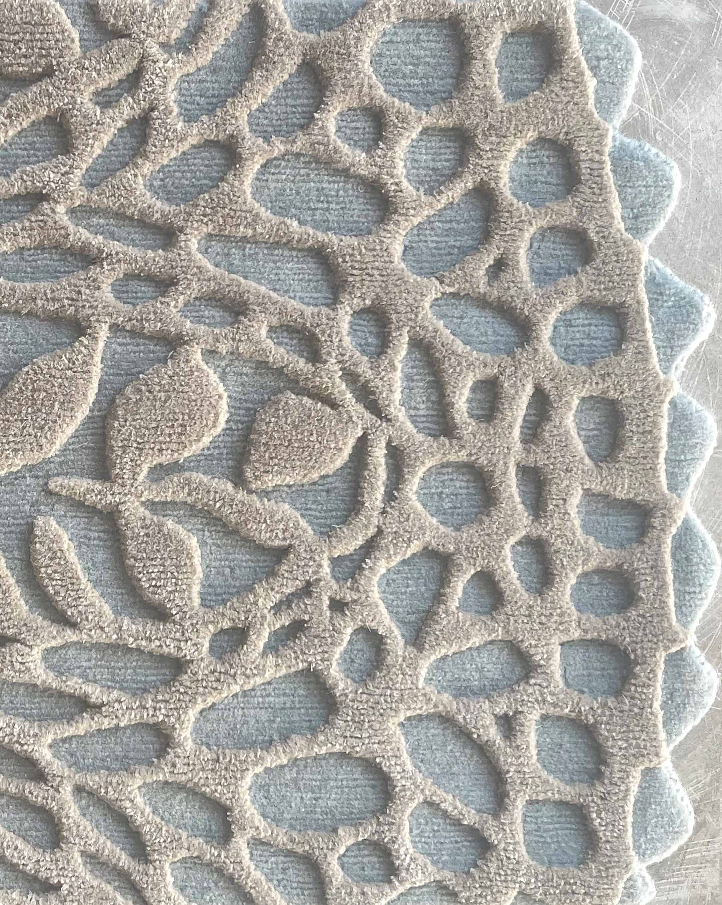 In the Cielo colorway, a Nonna’s Lace rug swatch shows the silk and wool pattern in blue and neutral tones.