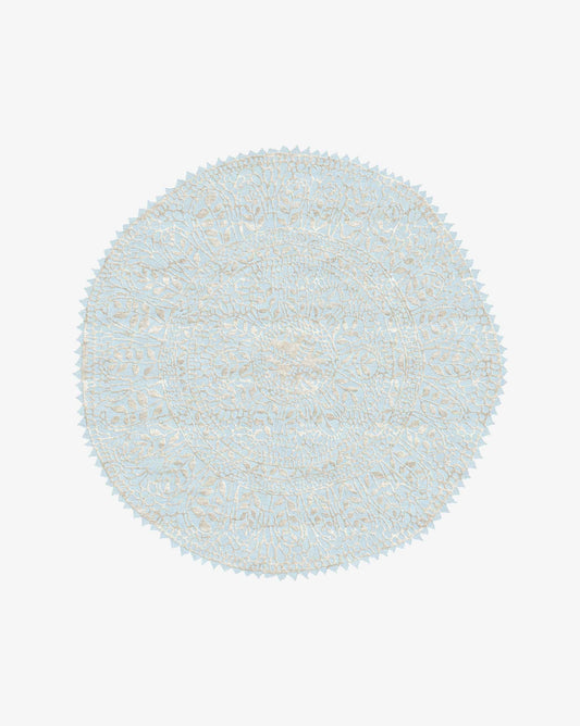 A Nonna’s Lace rug in the Cielo colorway is a round design in silk and wool with a blue background against a neutral high-pile lace pattern.