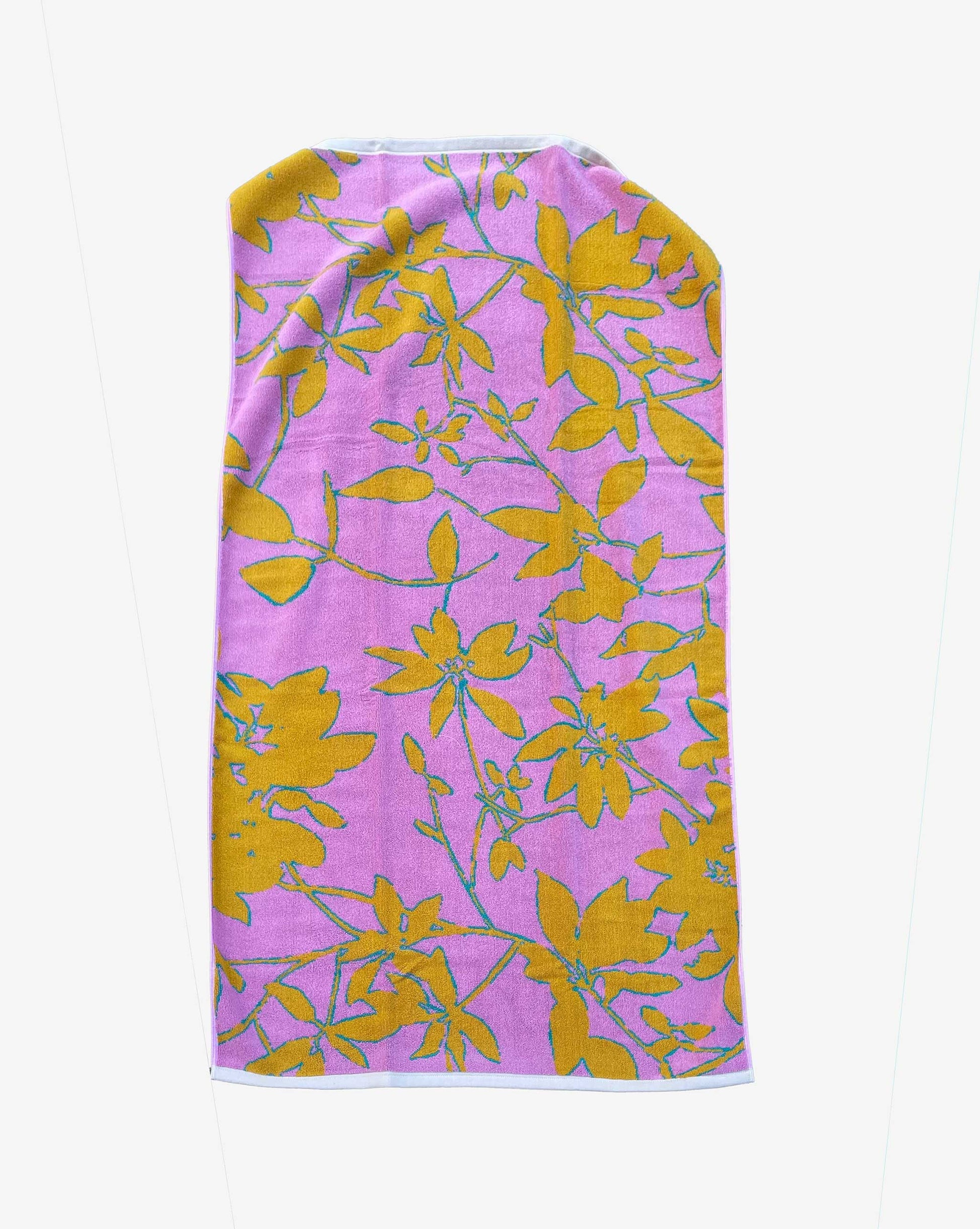 The Eskayel x Meleau Plumeria Shadows beach towel incorporates soft pink, golden orange, and teal.