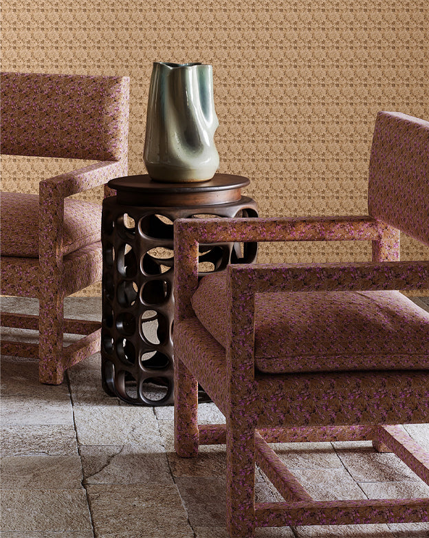Cropped image of two patterned chairs in Eskayel's Alheli fabric in Rubra — a brown-and-magenta microprint — with a decorative table and vase. 