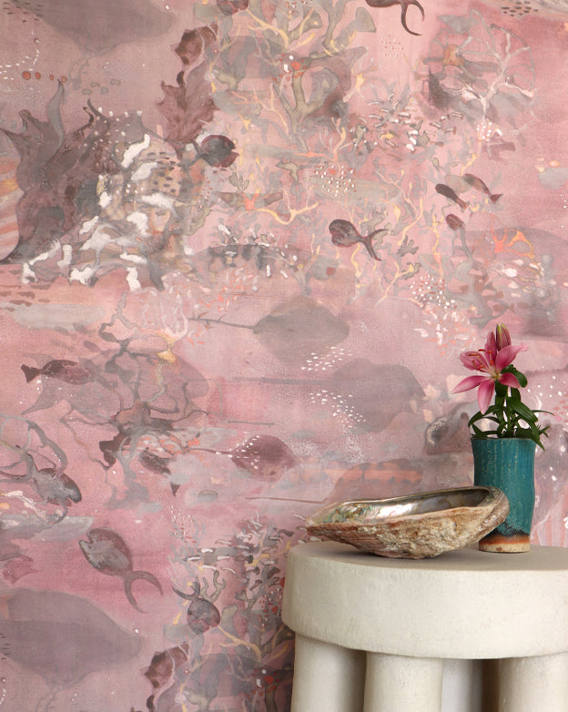 Light red wallpaper with an underwater scape design, table with decorative items.