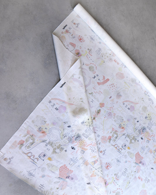 A partially unrolled sheet of 54" wide Vol de Nuit Fabric||Sunshine, featuring pastel-colored abstract designs and doodles on a grey surface reminiscent of oyster linen, sold by the yard.