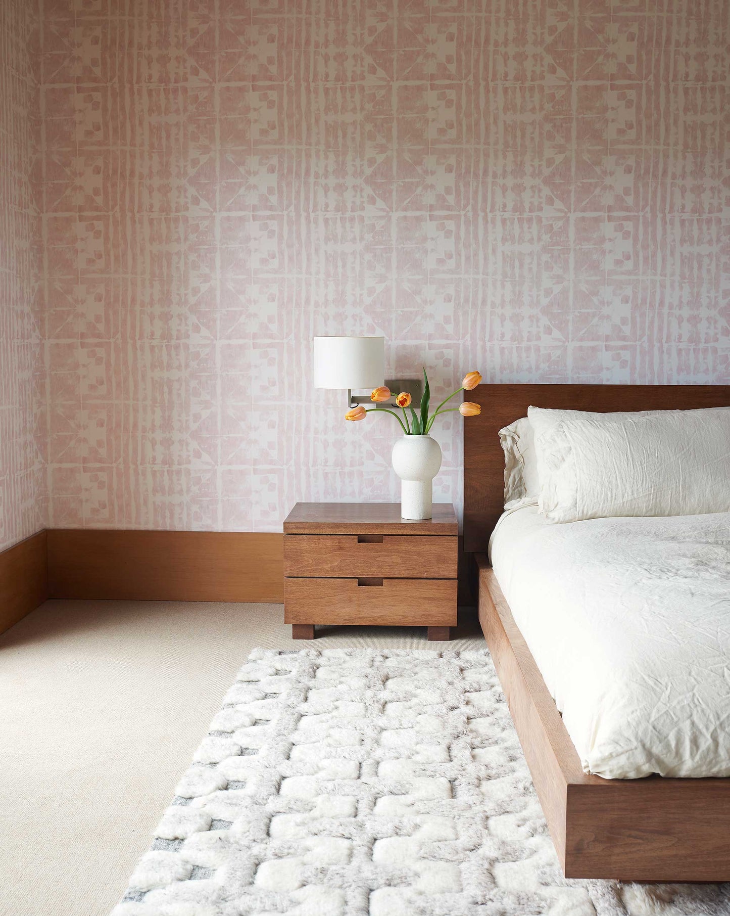 Eskayel's Banda Wallpaper in the colorway light peach installed in a bedroom with wooden and white accents.
