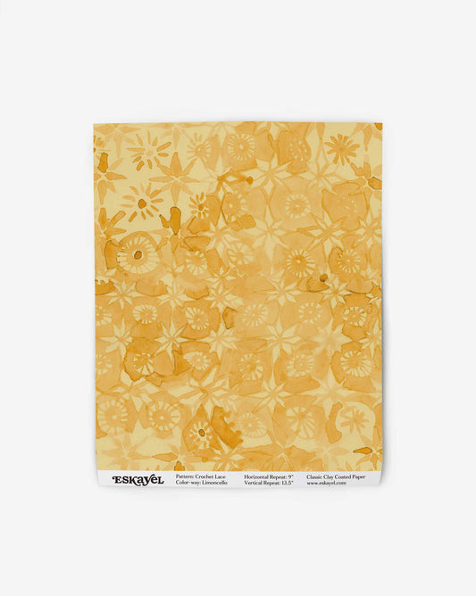 In a swatch of Crochet Lace wallpaper by Eskayel, the warm Limoncello colorway displays a micro-print of warm yellow hues.