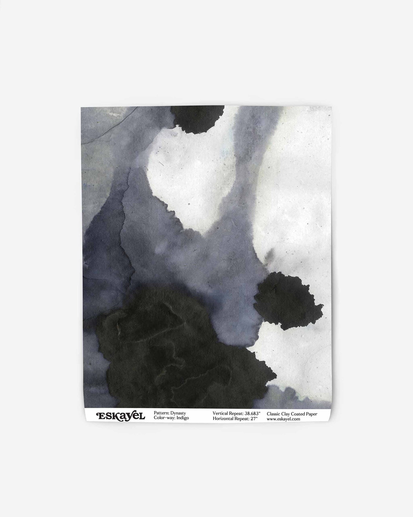 A piece of paper with an abstract black and gray watercolor pattern, featuring the brand name "Eskayel" and pattern details at the bottom, showcases the high-end Dynasty Wallpaper||Indigo in an exquisite Indigo colorway.