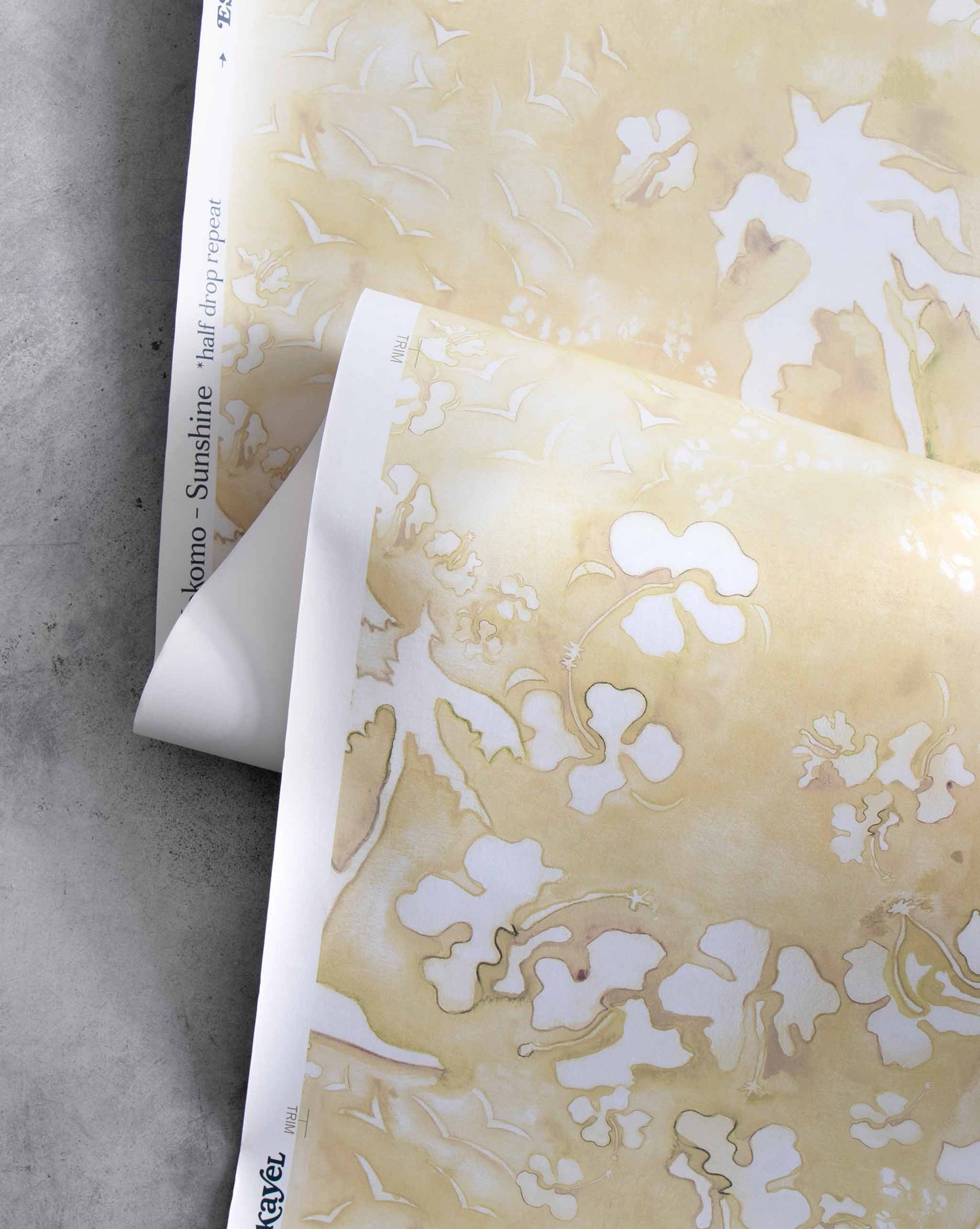 An image of Kokomo Sunshine Wallpaper with a yellow palette. The pattern is inspired by a tropical landscape of hibiscus lilies, birds, and palm trees using this idea to create one continuing line.