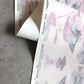 A detail shot of Madagascar Wallpaper in the colorway Rose which features a blue and pink pattern.