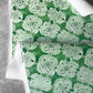 Green wallpaper with a white floral lace pattern on a gray surface.