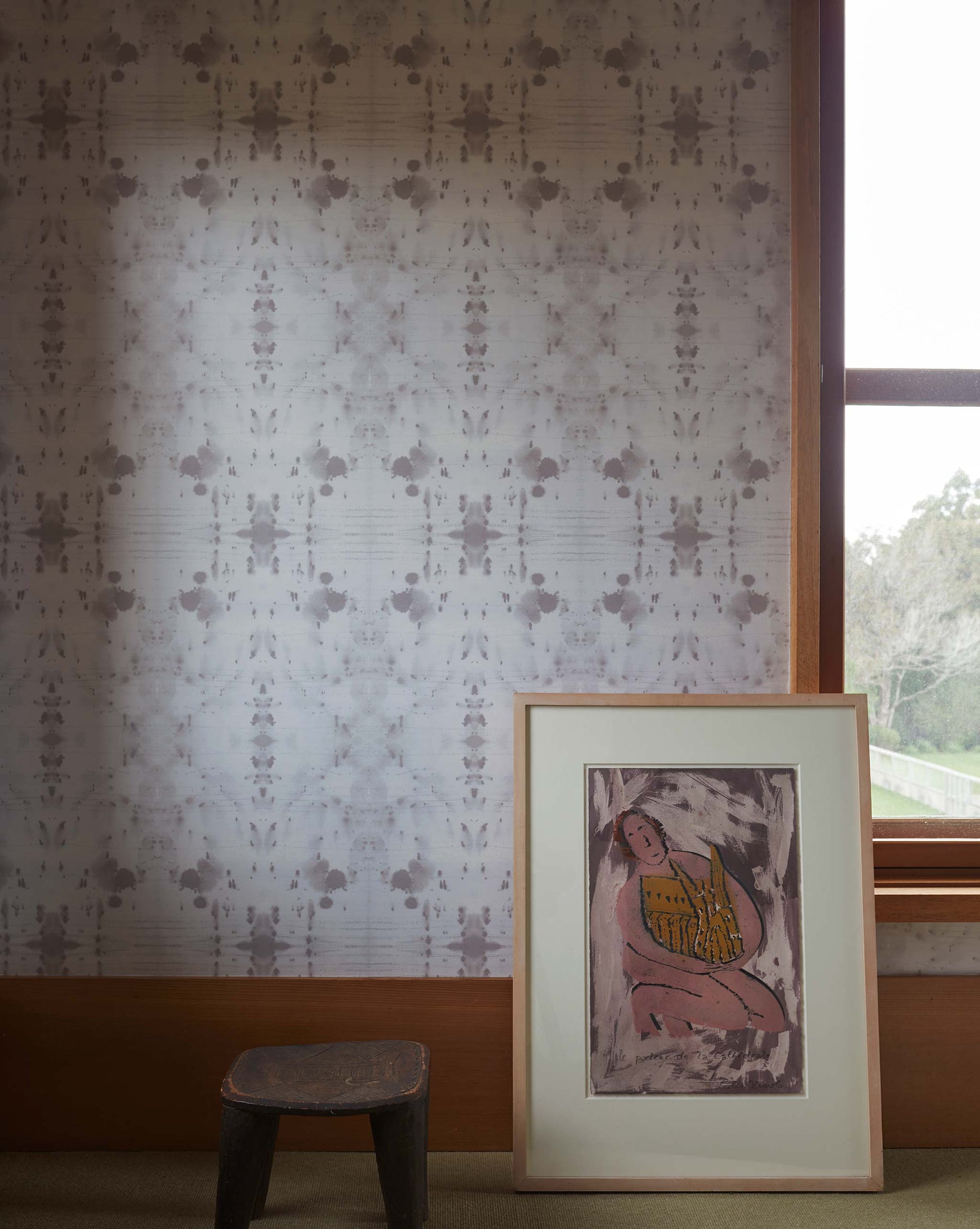 Eskayel's Nairutya Wallpaper in the colorway Chalk installed in a room with a wooden stool and framed artwork.