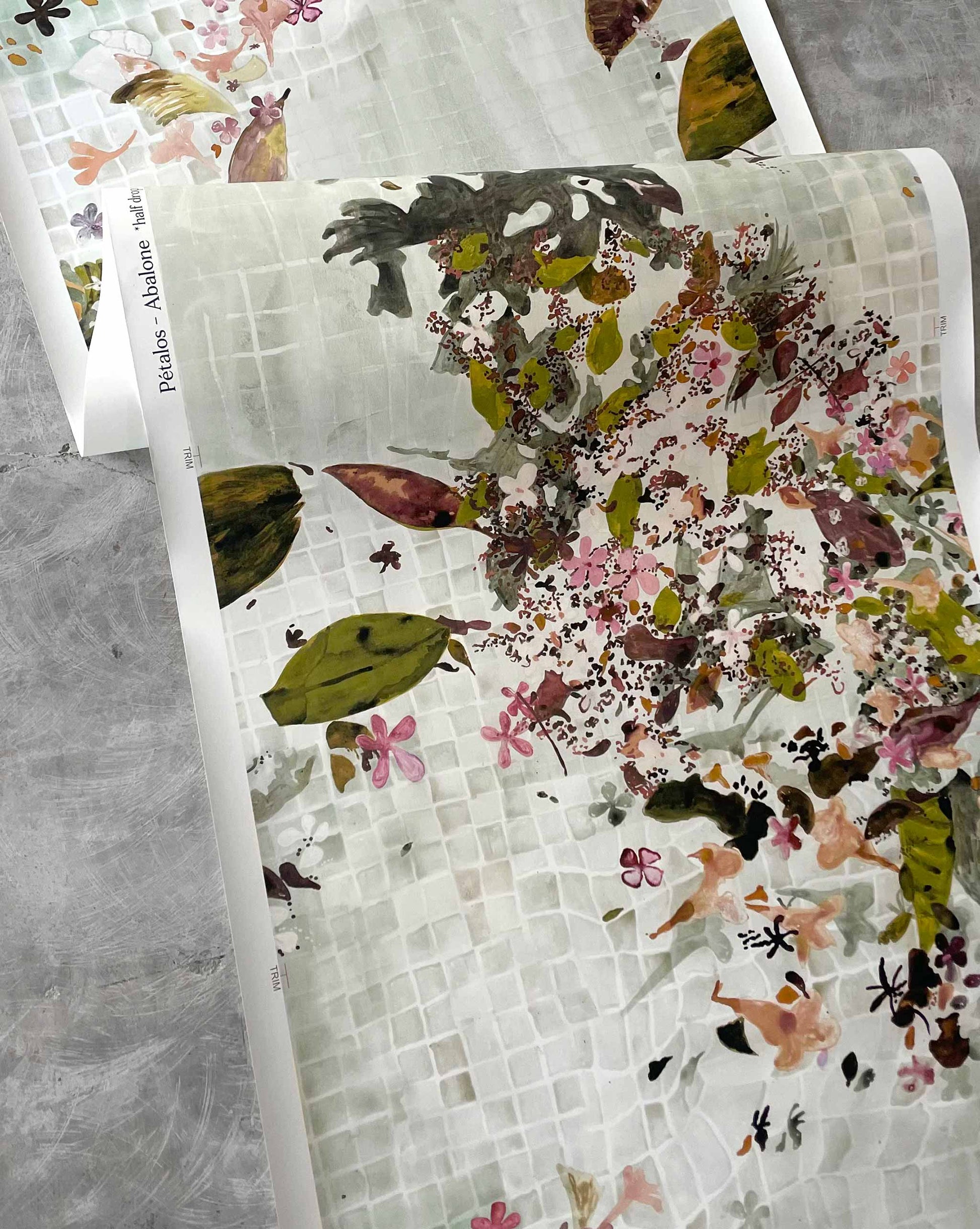 Shown flowing off a roll, Eskayel’s Pétalos wallpaper pattern in Abalone is based on a green palette with pink and brown accents.