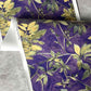 A detail photo of Eskayel’s Plumeria Shadows wallpaper pattern in Eggplant, a colorway of purple with green tones.