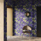 A room appointed with Eskayel’s Plumeria Shadows wallpaper pattern in Eggplant, a colorway of purple with green tones.