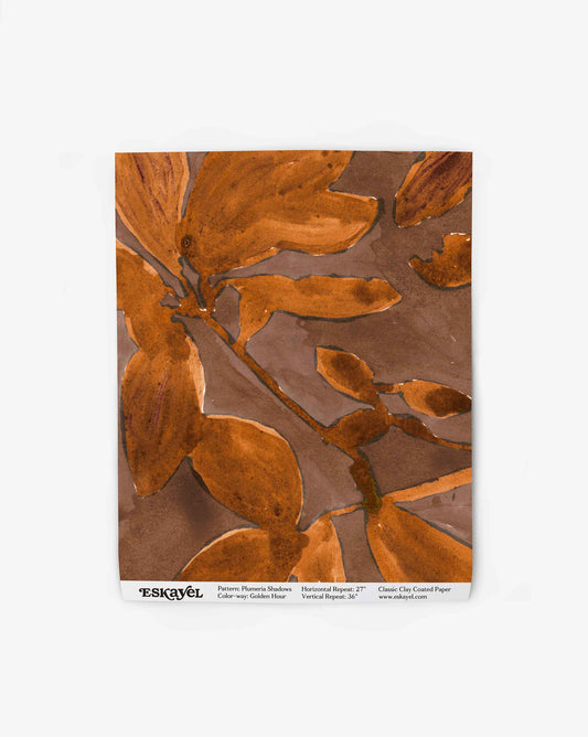 A wallpaper swatch image of Plumeria Shadows pattern in Golden Hour, a colorway featuring a rich brown background and gold tone leaves | Eskayel