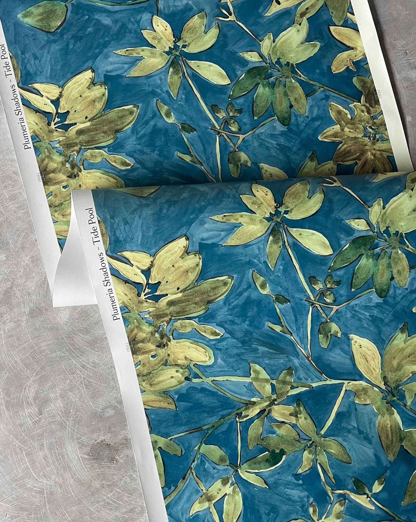 A detail photo of Eskayel’s Plumeria Shadows wallpaper pattern in Tide Pool, a colorway featuring a deep blue background.
