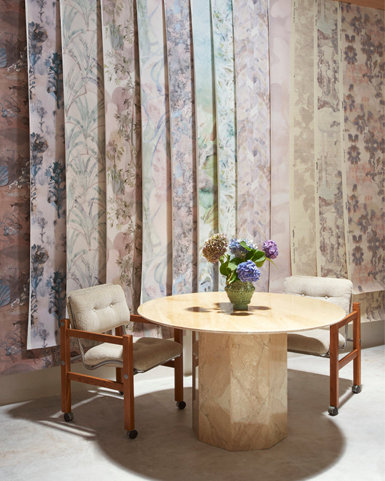 Round marble table with chairs against a wall filled with wallpaper drops.