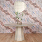 A table with a vase on it in front of a tiled wall decorated with Triangle Checks Wallpaper||Camel.