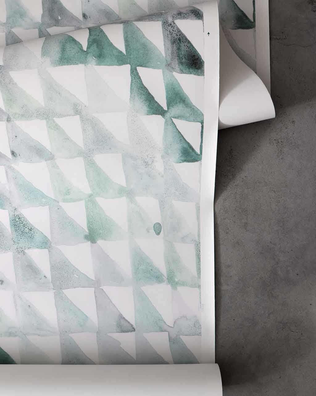 A roll of Triangle Checks Wallpaper Verde, featuring a green and white pattern on it