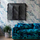 A blue sofa in front of a blue wall with Triangle Checks Wallpaper Verde design