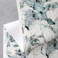 A folded piece of paper with the Cocos Grasscloth Chloros luxury blue and green floral pattern