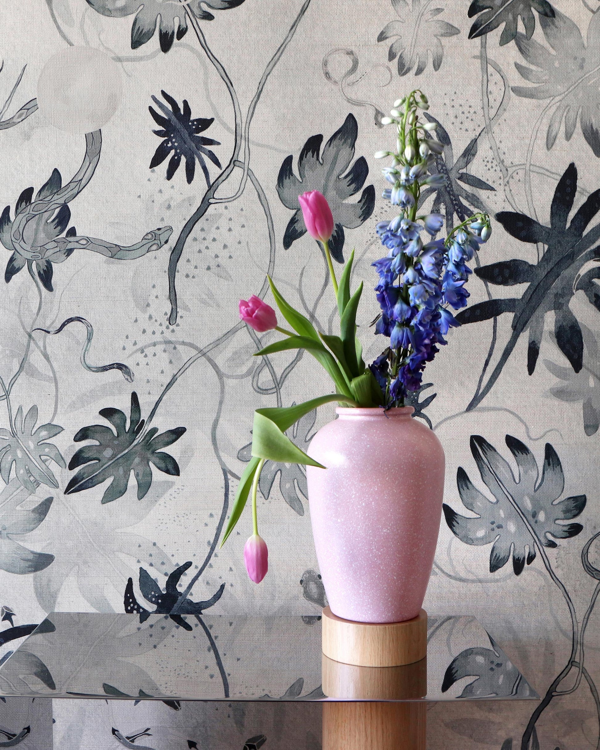 A pink Edera Grasscloth Ice vase with flowers in it on a chinoiserie-inspired table