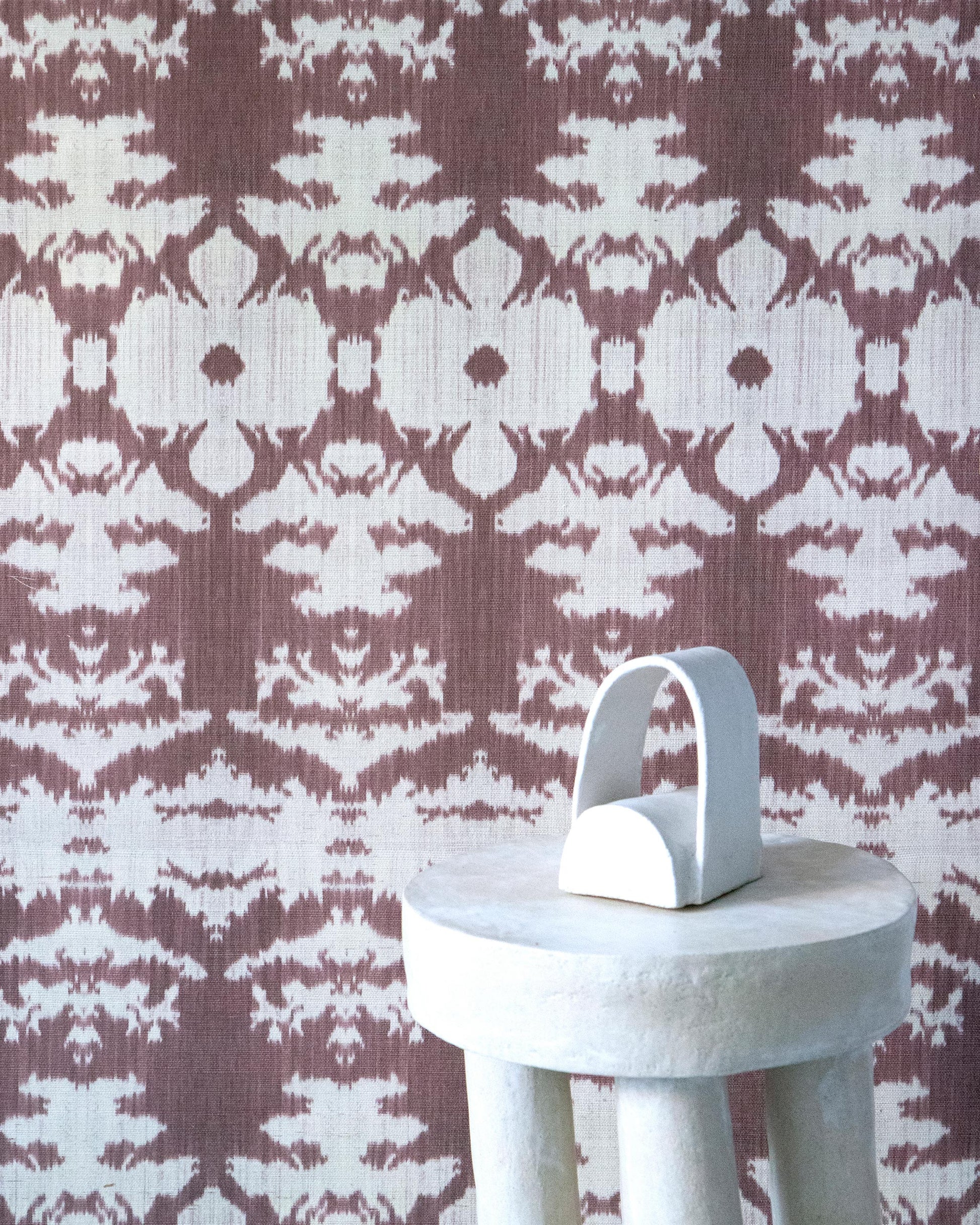 A white stool with a brown and white pattern from The Dance Grasscloth Morinda Ikat Collection