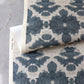 A floral pattern on a blue and white paper from the Lora Collection in The Dance Grasscloth Olive colorway