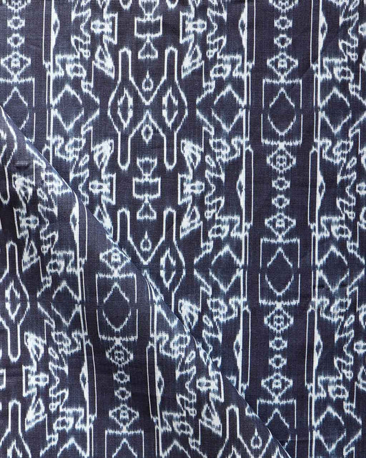 A close up of Akimbo Fabric Indigo Ikat with geometric designs, reminiscent of a vintage rug