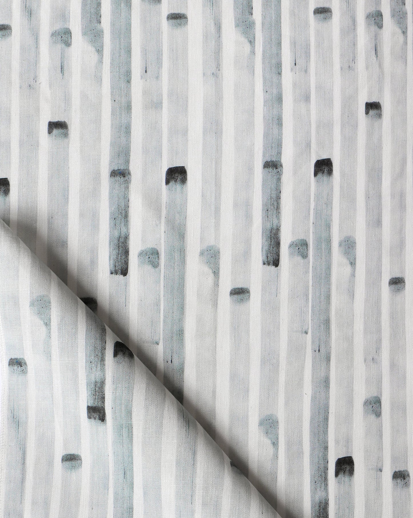 A close up of a grey and white fabric with black and white Eskayel Bamboo Stripe Fabric Slate pattern