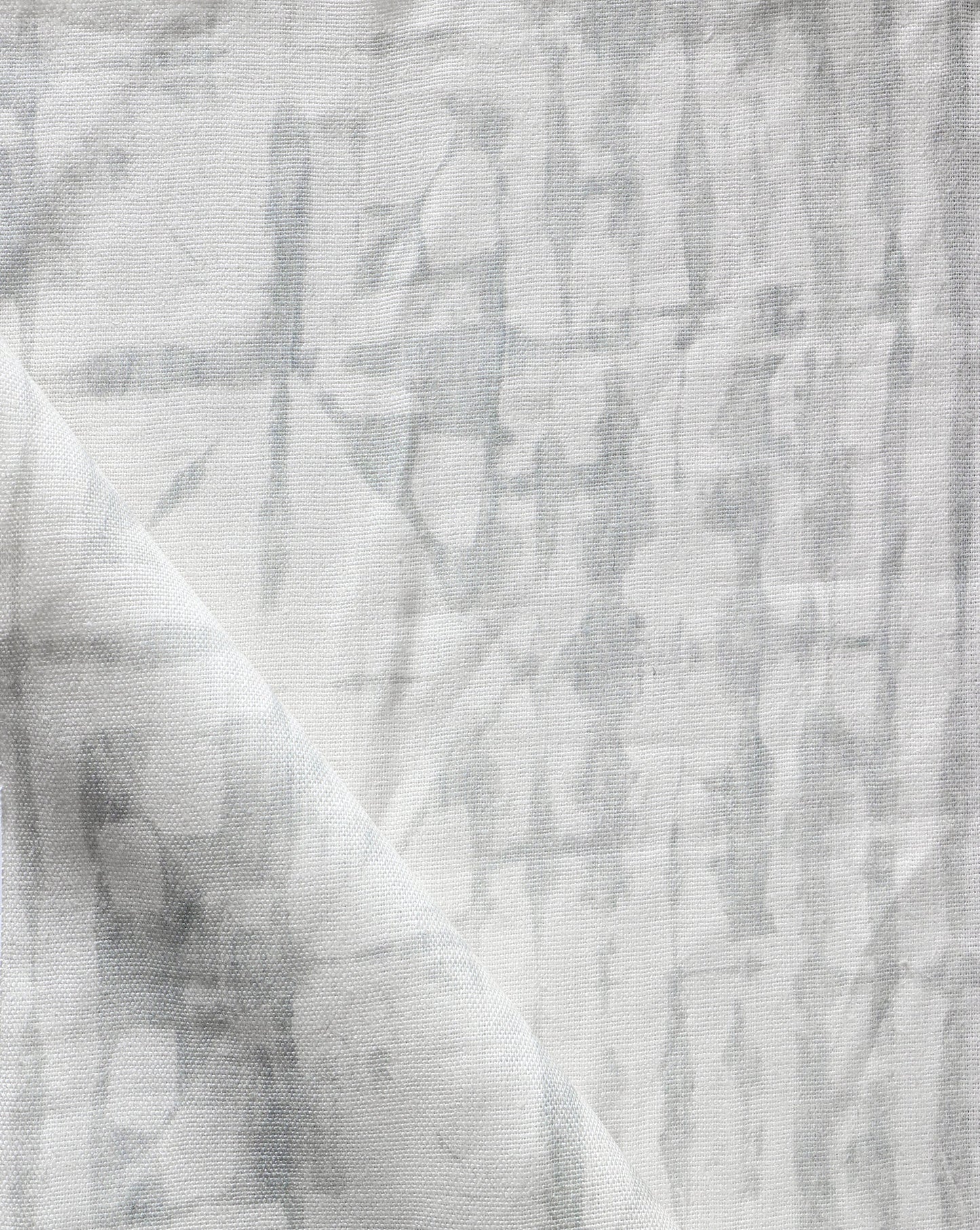 A close up of a white and gray Banda Fabric Bare by Eskayel, featuring shibori tie-dye patterns