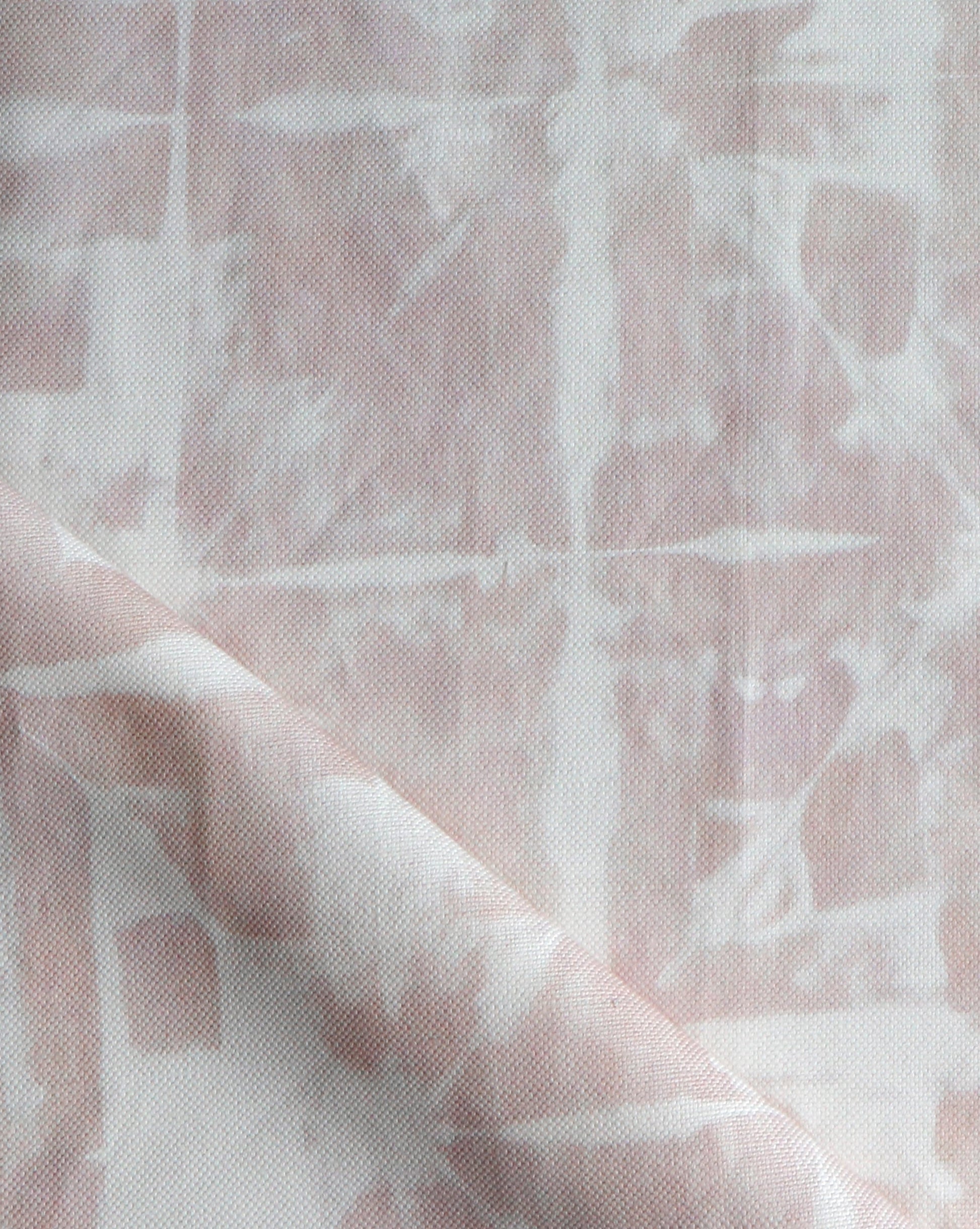 A close up of a pink and white fabric showcasing Banda Fabric Light Peach's tie-dye techniques