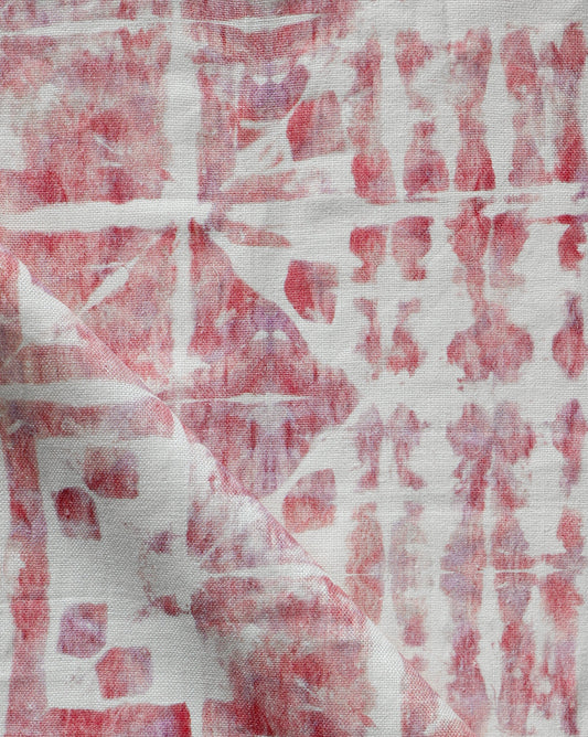 A red and white Banda Fabric with a tie-dye pattern on it