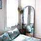 A small bedroom with a Mani Fabric Gulf bed and a mirror in turquoise colorway
