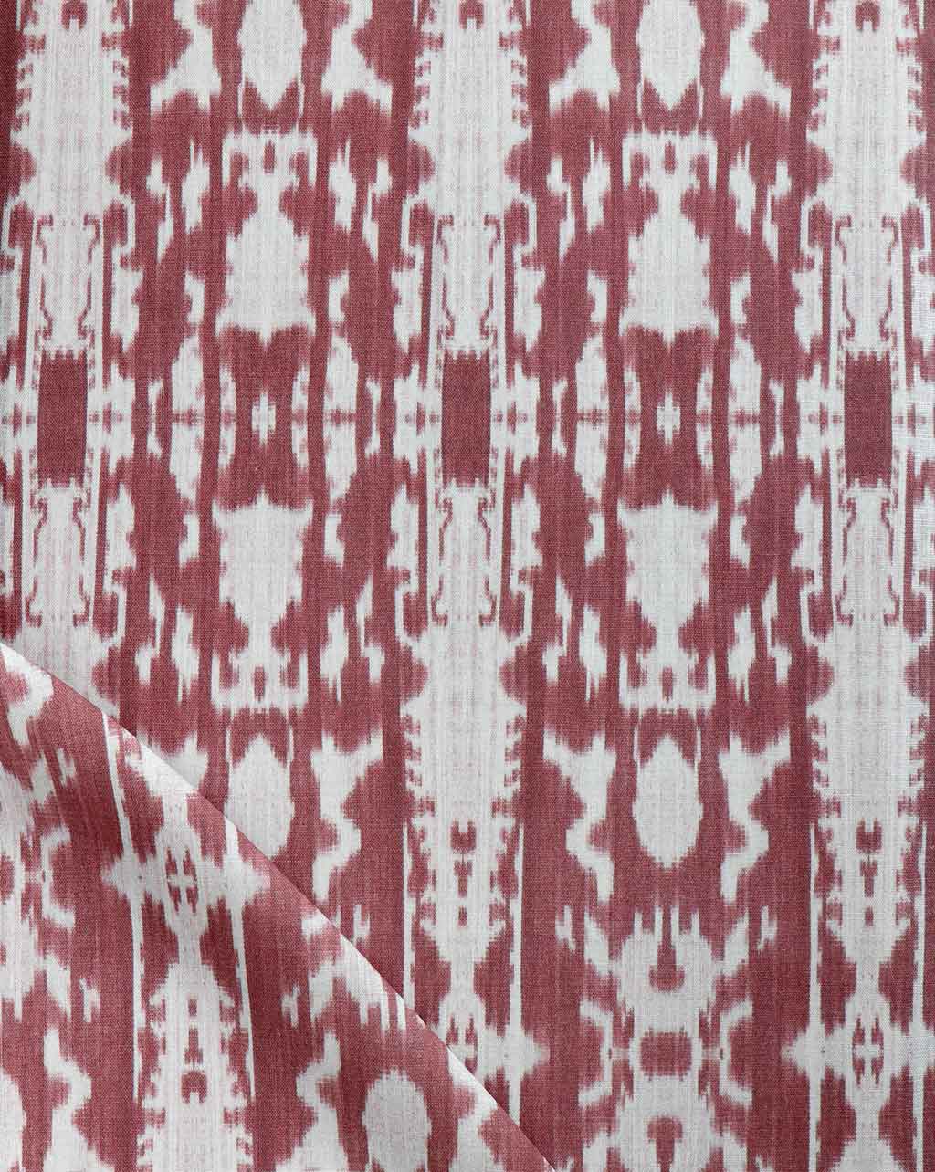 A close up of a red and white ikat fabric featuring the Biami Fabric Morinda Ikat pattern