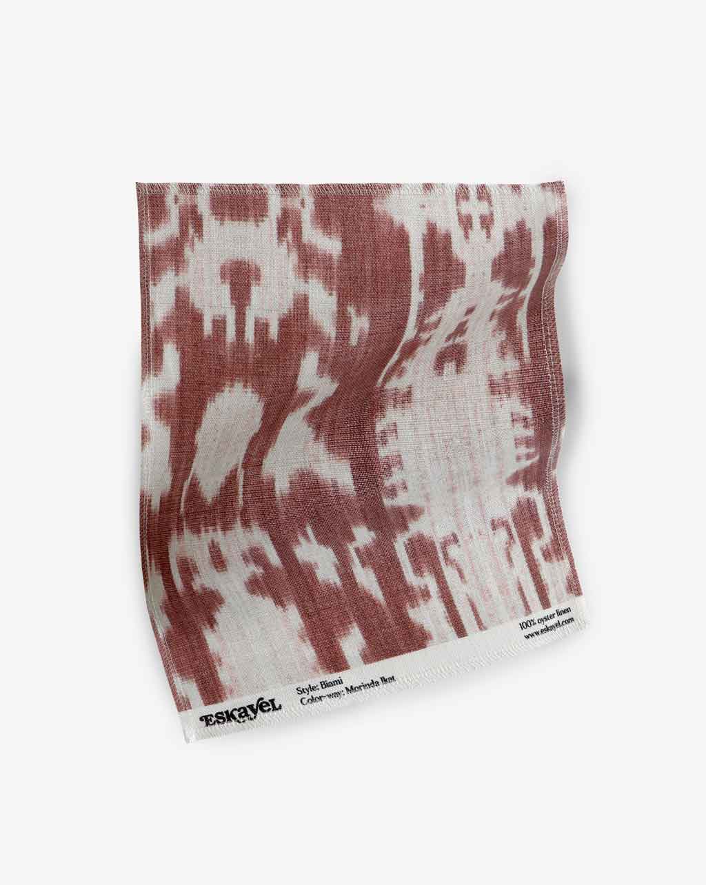A red and white ikat fabric with the Biami  Fabric Morinda Ikat pattern on a white background