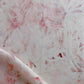 A close up of pink and white Cortile Fabric Pelle paint on a piece of fabric, perfect for custom pillows or rugs