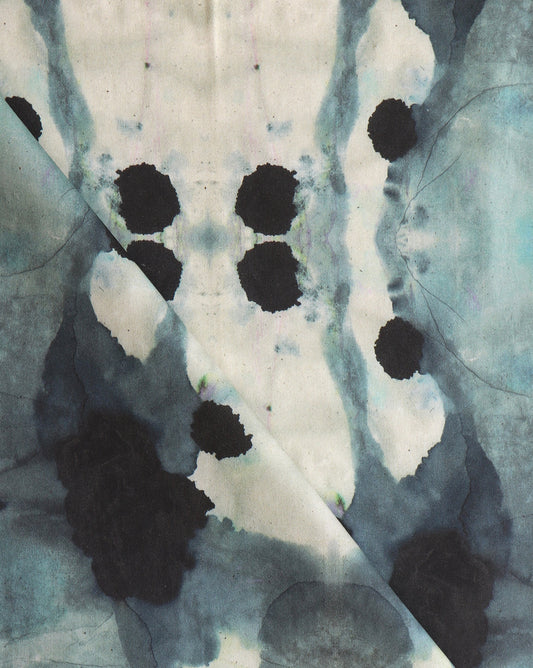 A close up of a blue and black ink stain on a piece of Dynasty Fabric Slate with an ink blot design