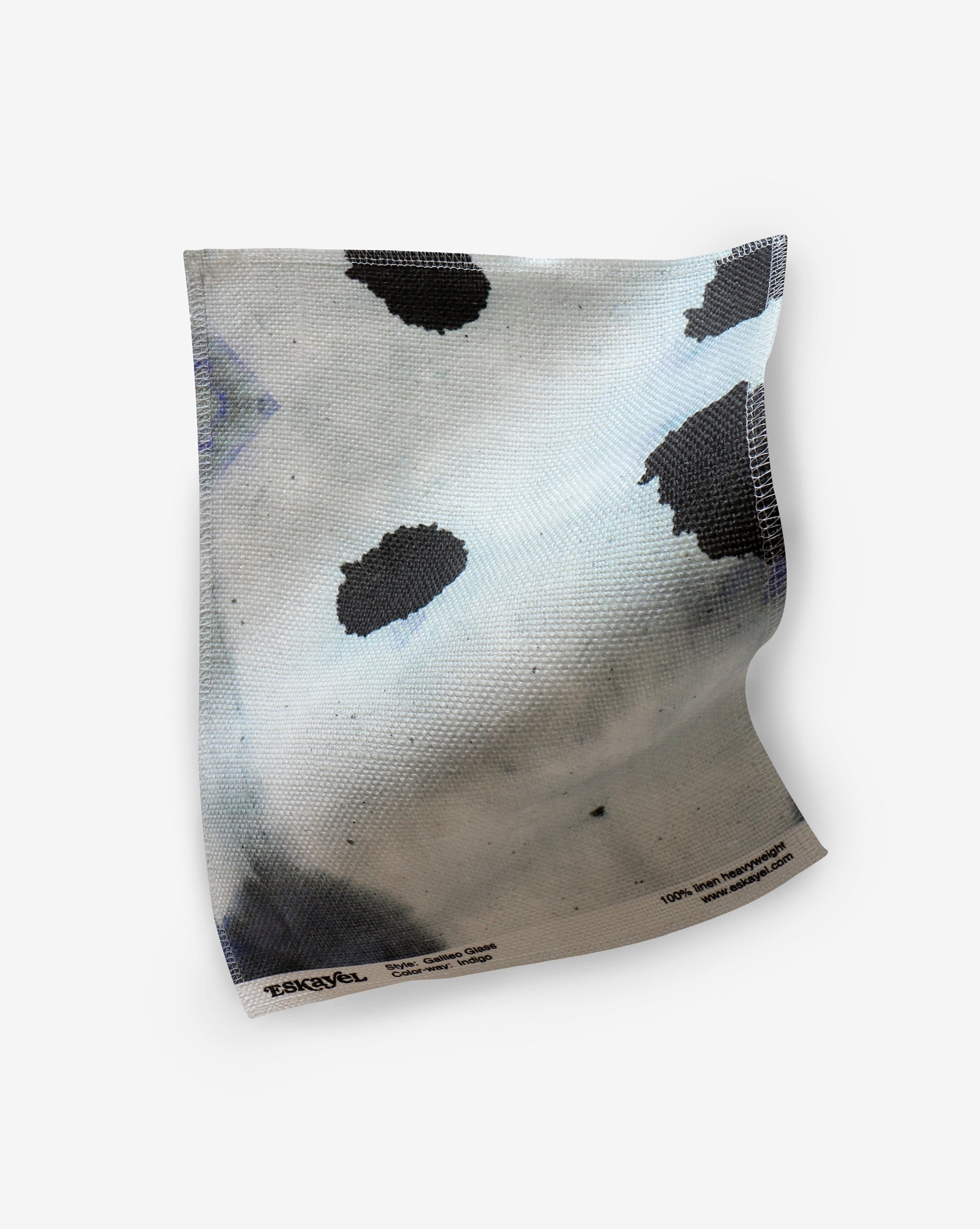 A luxury Galileo Glass fabric with fluid pigments creating black spots on a white cloth