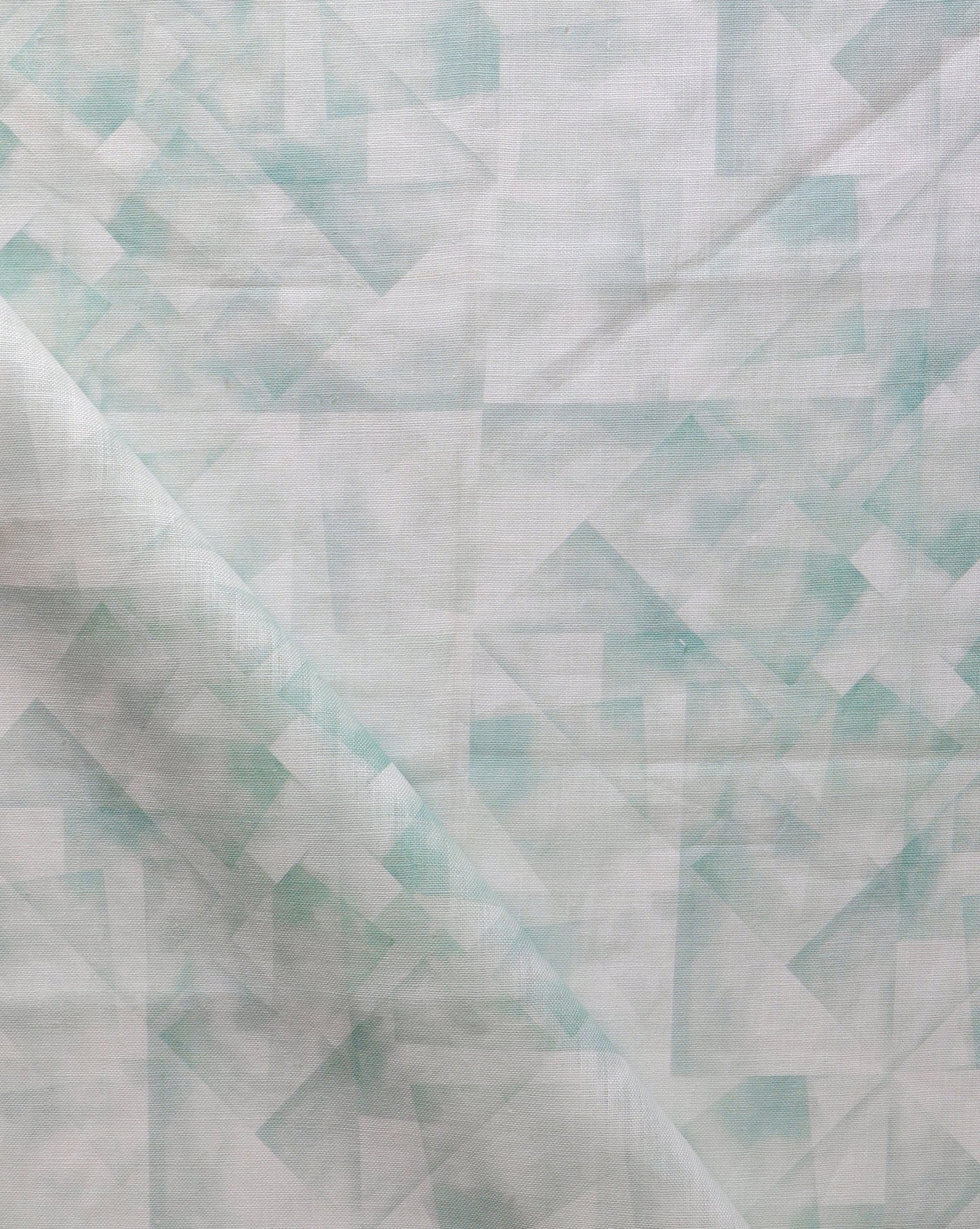A close up of a green and white quilted Kalos Fabric||Sage kaleidoscope style collage fabric.