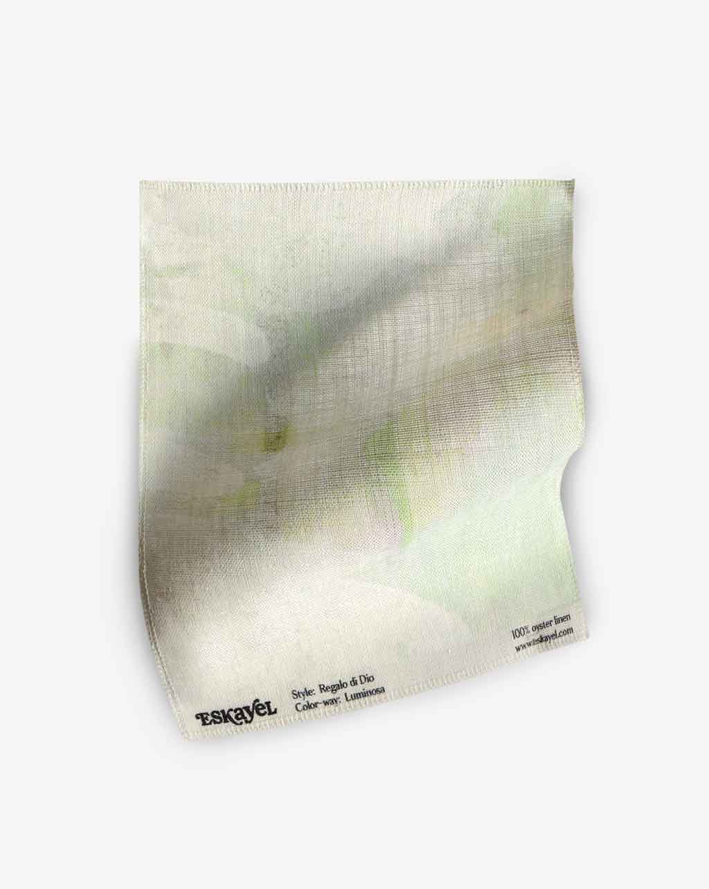 A white Regalo di Dio Fabric Luminosa with pale greens and green and white flowers on it