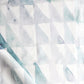 A close up of Triangle Checks Fabric Verde, a white fabric with a geometric pattern